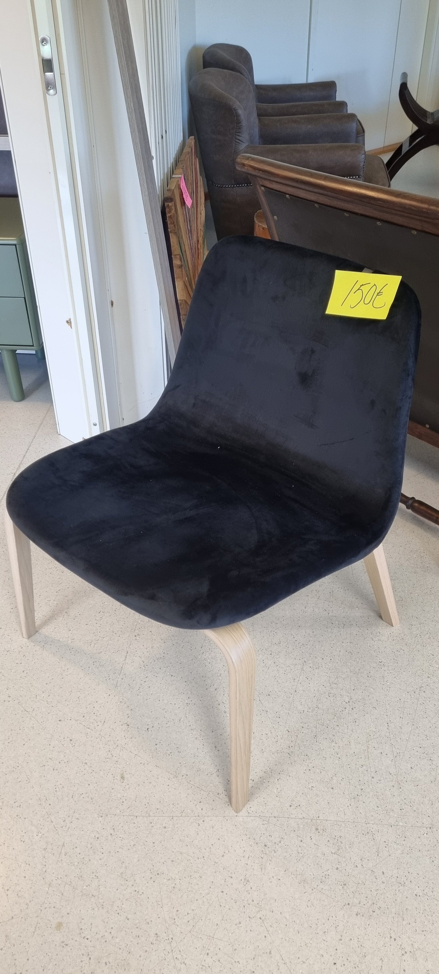 Yksittäiskappaleena musta, samettipintainen nojatuoli.