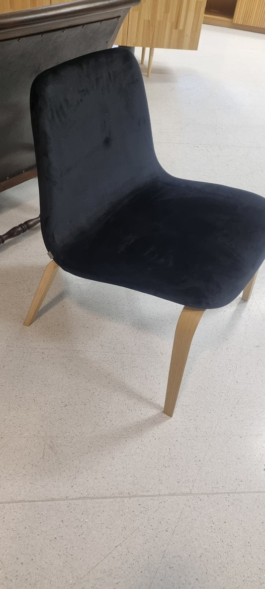 Yksittäiskappaleena musta, samettipintainen nojatuoli.